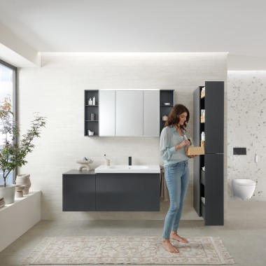 Femme ouvrant une colonne haute avec beaucoup d’espace de rangement pour une salle de bains moderne, Geberit Acanto